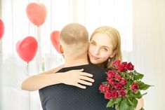 a man and woman hug each other in front of balloons, roses and heart - shaped balloons