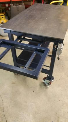 a table that is sitting on top of a dolly in a garage with other tools