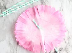 two paper plates with straws on top of them and one has pink flower petals