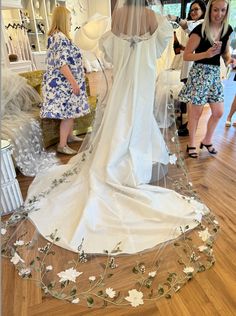 a bride's wedding dress is on display at the bridal shop while two women look on