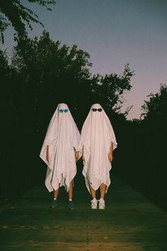 two people in ghost costumes walking down a path