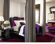 a bedroom with four poster bed and purple drapes on the walls, along with pink carpeted flooring