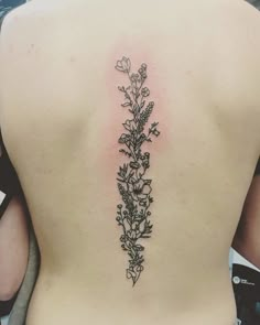 the back of a woman's lower back tattoo with flowers and leaves on it