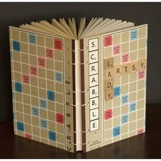 an open book with scrabble letters on the front and back cover, sitting on a table