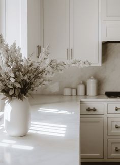 a vase filled with flowers sitting on top of a kitchen counter