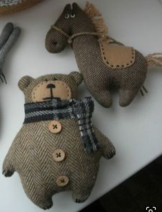 three stuffed animals are sitting on a table together, one is brown and the other is black