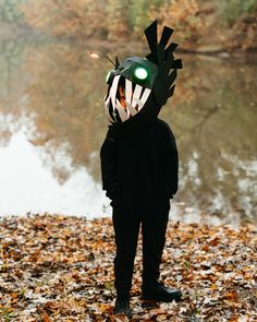 a young boy wearing a green helmet and standing in leaves