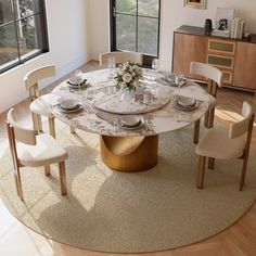 a dining room table with chairs and plates on it in front of a large window