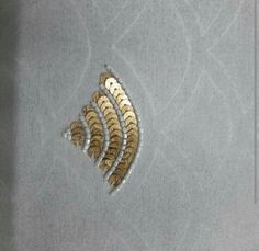 three gold feathers on a gray background with white and black circles in the middle,