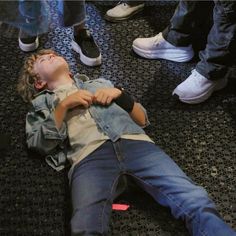 a young boy laying on the floor with his eyes closed