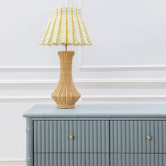 a lamp sitting on top of a dresser next to a white and yellow striped lampshade