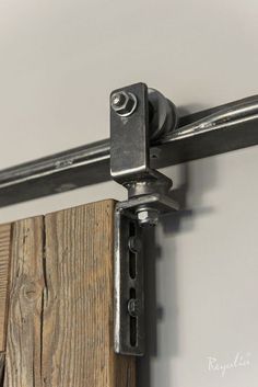 a close up view of a metal handle on a wooden door with white walls in the background