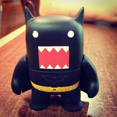 a black toy with red and white teeth on it's face sitting on a table