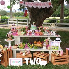 there is a table that has some food on it in front of a tree with balloons