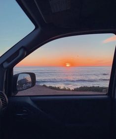 the sun is setting over the ocean as seen from inside a car