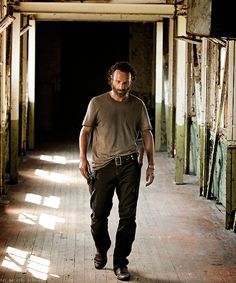 a man walking down a long hallway in an abandoned building