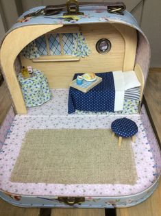 an open suitcase sitting on top of a wooden floor next to a table and chair