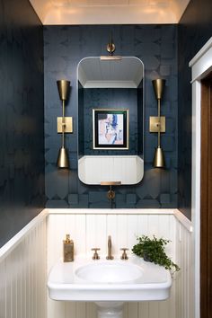 a white sink sitting under a bathroom mirror next to a wall mounted faucet