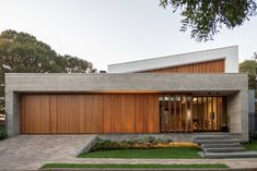 a woman walking past a modern house with wooden slats on the front and side