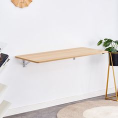 a wooden table sitting on top of a white floor next to a potted plant