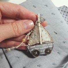 someone is holding a small sailboat ornament in their hand and it looks like they are made out of fabric