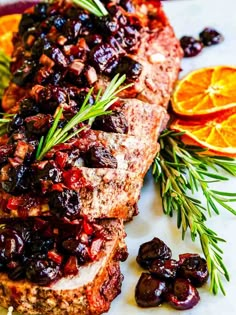 meatloaf with cranberry sauce and orange slices on a plate next to rosemary sprigs