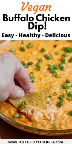 a hand dipping a tortilla chip into a bowl of buffalo dip