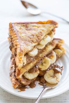 a white plate topped with a cut in half sandwich and banana slices on top of it