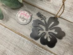 two metal tags sitting on top of a wooden table next to a potted plant