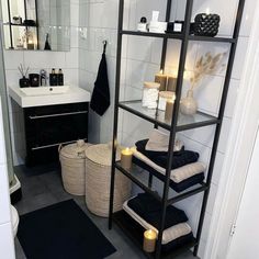 a black and white bathroom with candles on the shelves