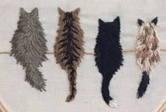 four different colored feathers are hanging on a white piece of cloth in the shape of a cat