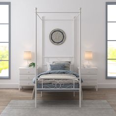 a white bed sitting in a bedroom next to two windows