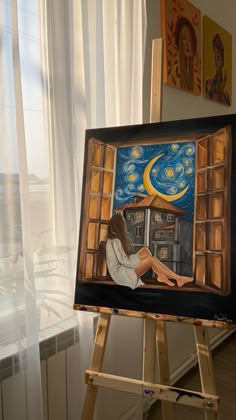 an easel with a painting on it in front of a window