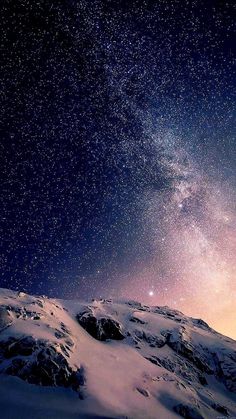 the night sky is filled with stars above a snow covered mountain range and some rocks