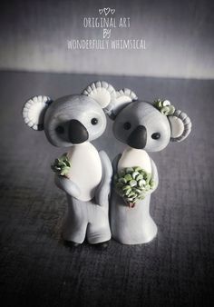 two ceramic koalas are standing next to each other with flowers on their heads