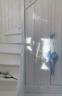 an umbrella is hanging on the wall next to some white stairs and a blue towel