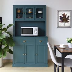 a microwave oven sitting on top of a blue cabinet next to a potted plant