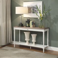 a white table with two vases on it and a lamp in front of it