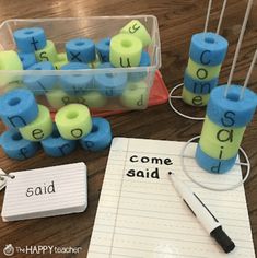 some blue and green letters are on the table next to a pen, paper with writing