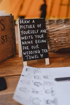 a sign that says draw a picture of yourself and write your name below for our wedding tea towel