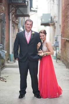 a man and woman in formal wear standing next to each other on a street corner