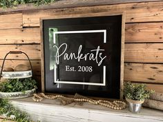 a sign that says pankrats est 2008 on it next to some potted plants