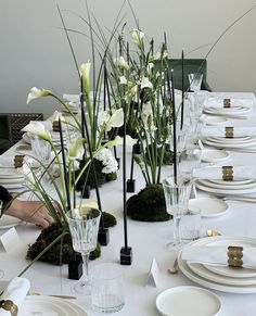 a long table is set with white flowers and place settings for the guests to sit at