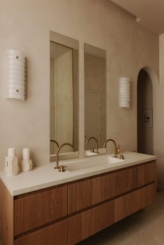 a bathroom with two sinks and mirrors on the wall next to each other in front of a light fixture