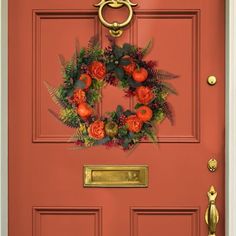 a red front door with a wreath on the side and gold handles to match it