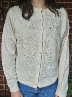 Beautiful beadwork embellishes this 1970/80s sweater from top to bottom.  White and irridescent beads for various shapes and sizes give this cardigan an elegant dimensionality. Nine pearly round buttons, beaded hem and cuffs, and lined body.  Size S/M: model is 5'3" and 120 lbs.  Measures 24" from neck to hem at back, 18 3/4" from side seam to side seam at armpits.  Sleeve inseam is 19".  A couple of mothworn spots, as shown in last photo.  With the lining, they are not as noticeable as they would be otherwise.   For more vintage treasures, please visit my shop @http://etsy.com/shop/Ampersand21716  Want to pick up from our bricks & mortar store in Brunswick, Maryland? Use Promo Code 21716 to remove shipping and send us a message to make arrangements.     I make every attempt to ship within Winter Embellished Long Sleeve Cardigan, Embellished Long Sleeve Cardigan For Winter, Long Sleeve Embellished Cardigan For Winter, Embellished Fitted Sweater For Spring, Elegant Embroidered Winter Sweater, Elegant Embroidered Winter Cardigan, 80s Sweater, 120 Lbs, Beautiful Beadwork