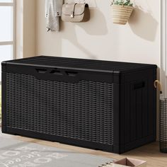 a large black storage box sitting on top of a wooden floor next to a window