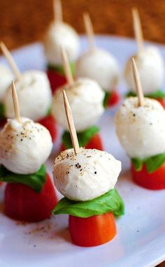 small appetizers with toothpicks and tomatoes on a white plate, ready to be eaten