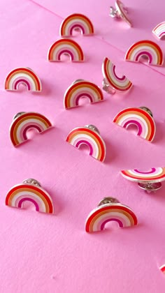 several pieces of paper that are shaped like rainbows on a pink surface with silver rings