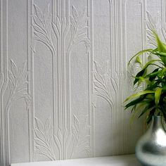 a potted plant sitting on top of a white shelf in front of a wall